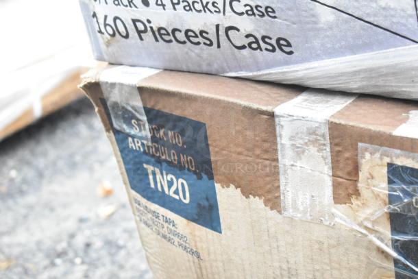 Box labeled "STOCK NO. TN20" containing new scratch and dent items: towel wipes, food cups, cold cups, gloves.