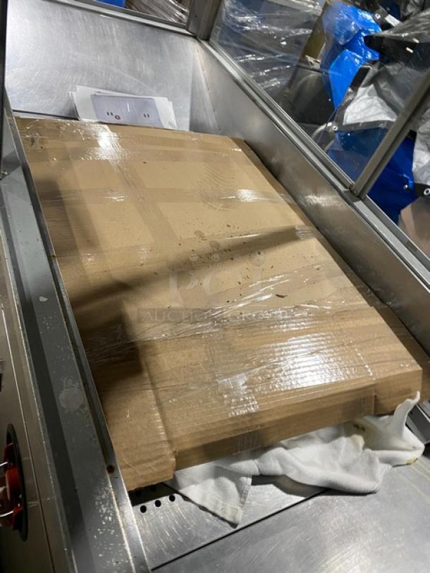 Cardboard box on a stainless steel surface, likely packaging for a Gold Medal Model 2973137 popcorn popper.