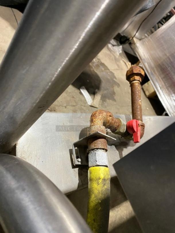 Cleveland Range stainless steel gas-powered tilted braising pan on legs, showing connection piping and red valve, in used condition.