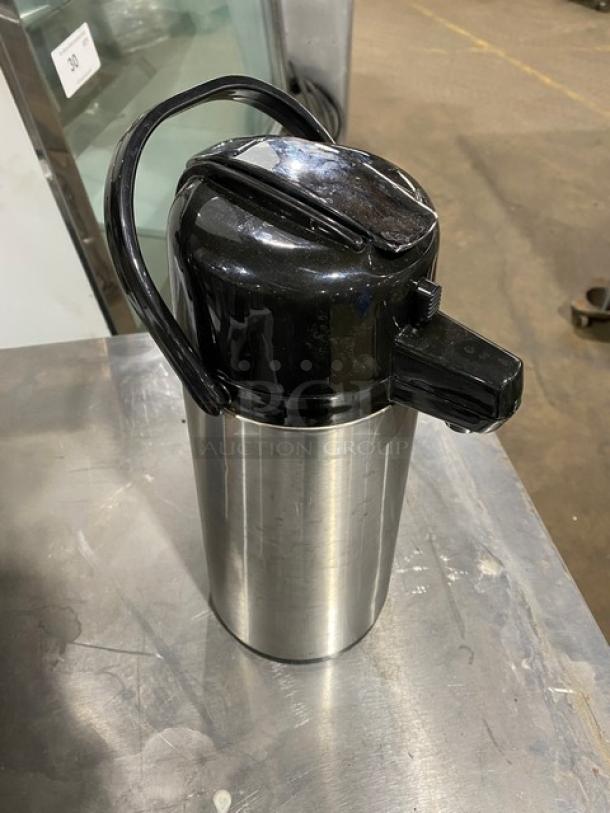 Stainless steel insulated beverage dispenser, commercial-grade, with black plastic lid and handle. Appears in good condition.
