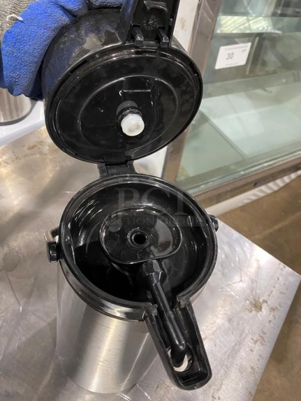 Stainless steel insulated beverage dispenser with open lid, showing interior. Used condition, suitable for commercial use.