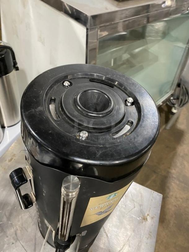 Fetco black insulated commercial beverage dispenser, Starbucks style. Features robust build, moderate wear. Plastic handle.