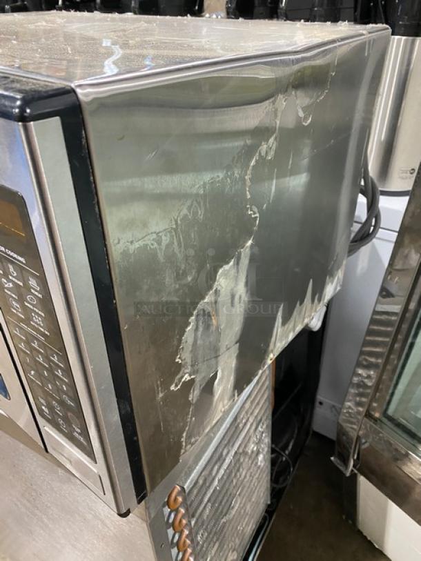 GE Appliances stainless steel countertop microwave, model JES1651SJ02 from 2009. Notable exterior wear and damage visible.