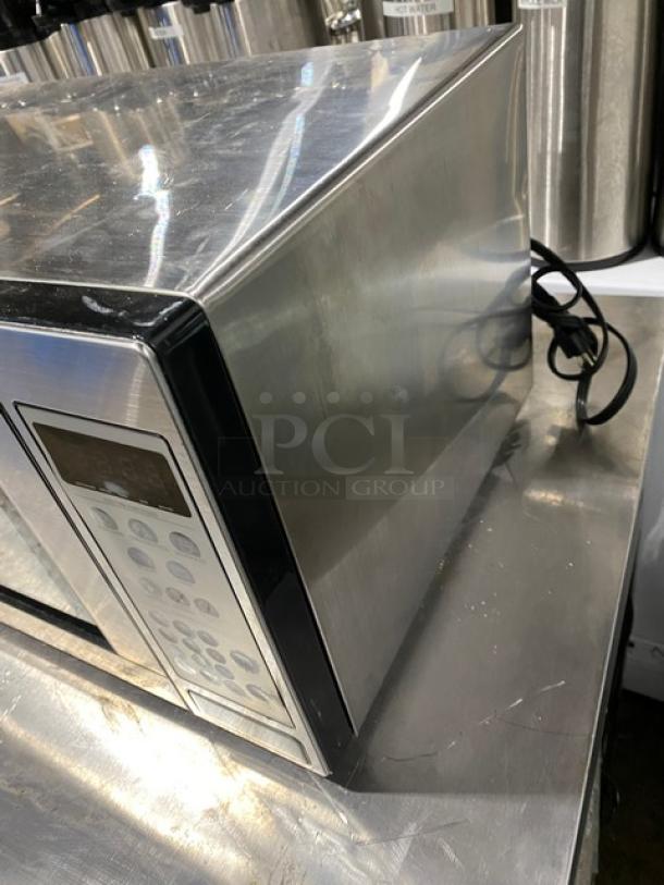 GE commercial stainless steel microwave, model JES1142SJ06, 2010, electric-powered, countertop design. Visible wear.