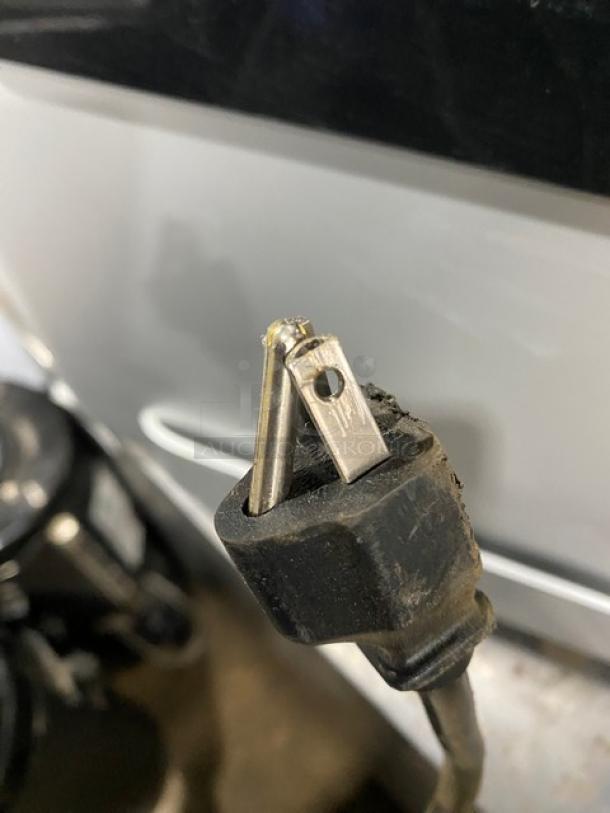 A close-up of a two-prong electrical plug for the Mars Drinks 2016 Flavia Creation Series coffee machine, showing wear.