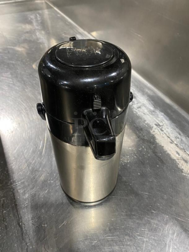 Commercial stainless steel insulated beverage dispenser with black plastic lid and push lever. Good condition.