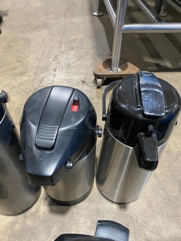 Commercial stainless steel insulated beverage dispensers with black lids, used condition, ideal for hot or cold drinks.