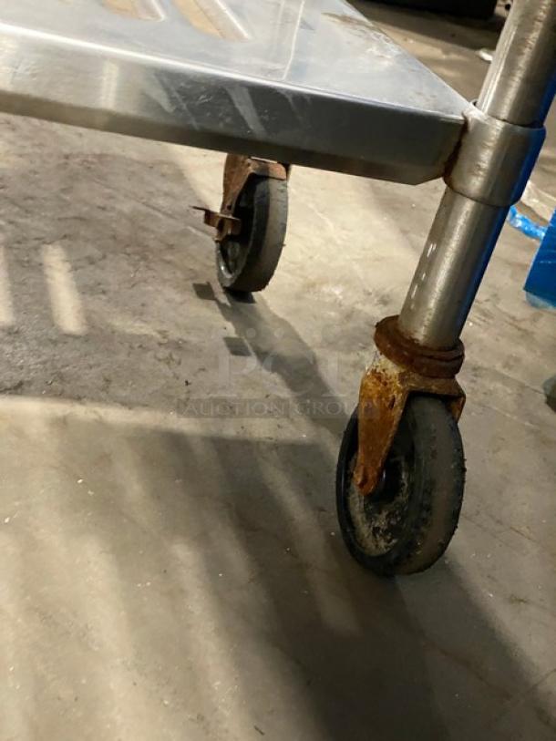 Commercial heavy-duty 4-tier mobile utility rack on casters, rust on wheels, metal shelves, sturdy construction.