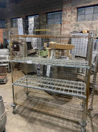 Commercial 4-tier mobile enclosed wired-rack storage cart on casters, used condition, with visible rust and sturdy metal construction.