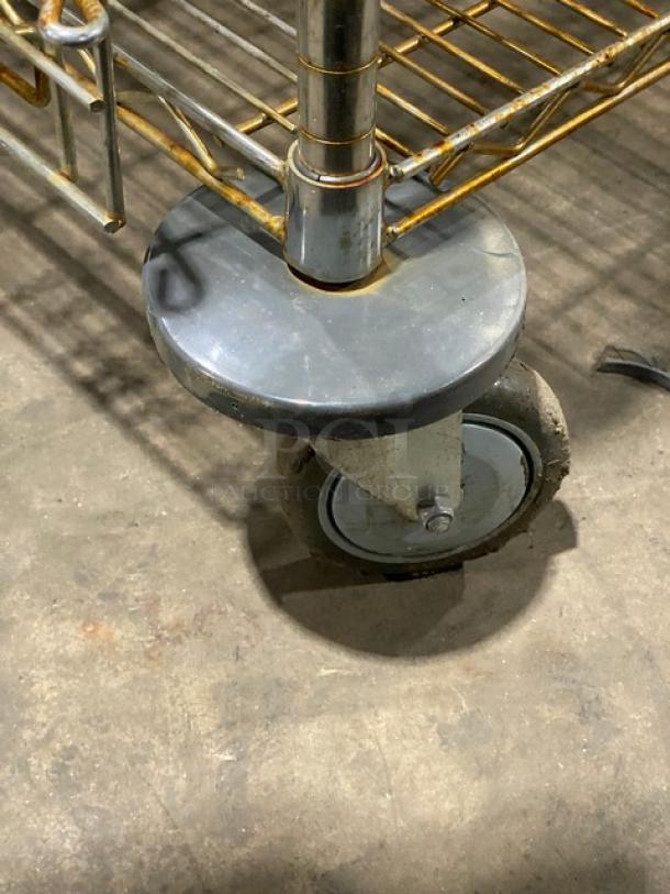 Commercial 4-tier mobile storage cart with enclosed wired racks, heavy-duty casters, minor wear visible.