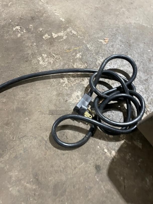 Coiled power cord for Beverage-Air UCR27A-24-23 undercounter refrigerator, showing standard plug, on concrete surface.