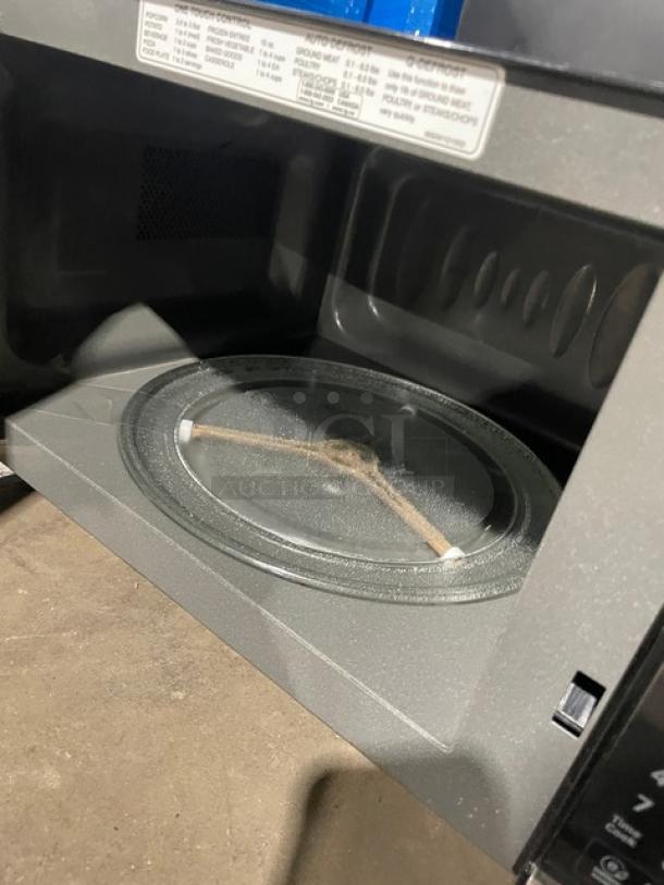 LG commercial stainless steel countertop microwave oven, Model LCS1112ST. Features one-touch digital control, 120V, 1 Phase. Visible labels detail settings. Appears in good condition.