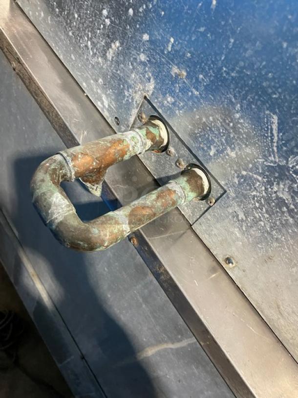Rusted metal pipes attached to a textured stainless steel surface, part of a Hoshizaki ice maker, model DCM-500BWF.
