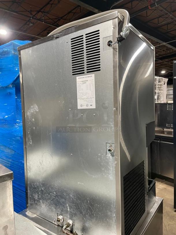 Hoshizaki DCM-500BAF stainless steel ice maker and water dispenser. Features air cooling, drip tray, and 115-120V 1 phase power. Appears in used condition. Model and serial number visible on label.