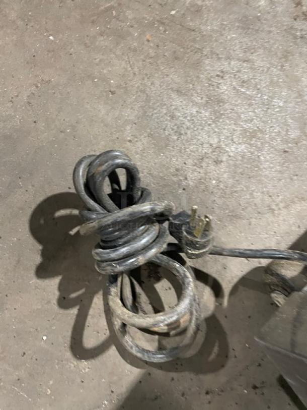 Beverage-Air UCR27 refrigerator power cord tied in a coil on concrete floor. Cord appears used, three-prong plug visible.