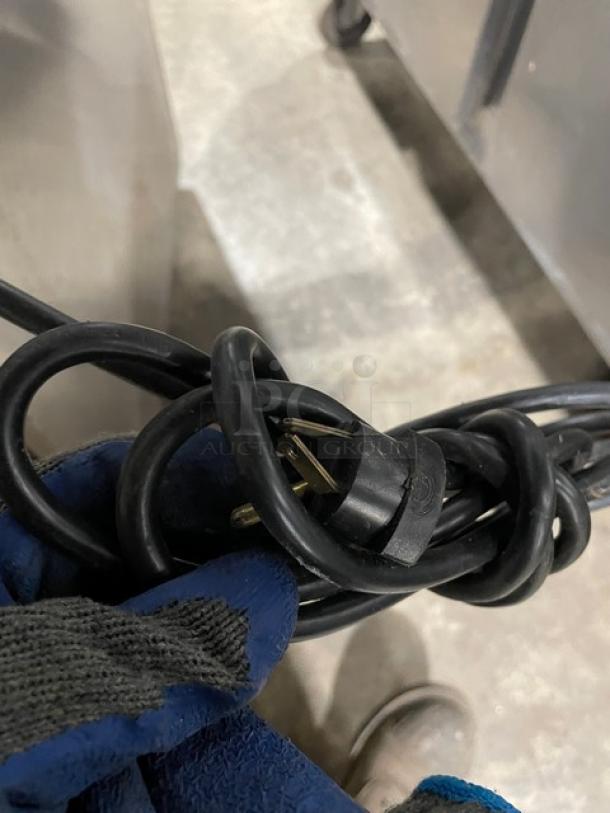 Curled power cord of Delfield Commercial Refrigerator, Model 406CADHLDD1, visible in a warehouse setting.