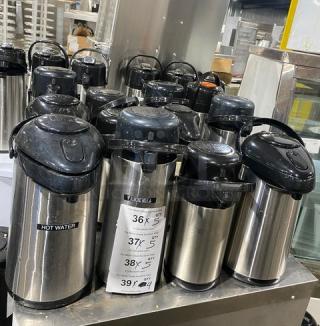 Stainless steel insulated beverage dispensers, commercial grade, multiple units. Features "HOT WATER" label, good condition.