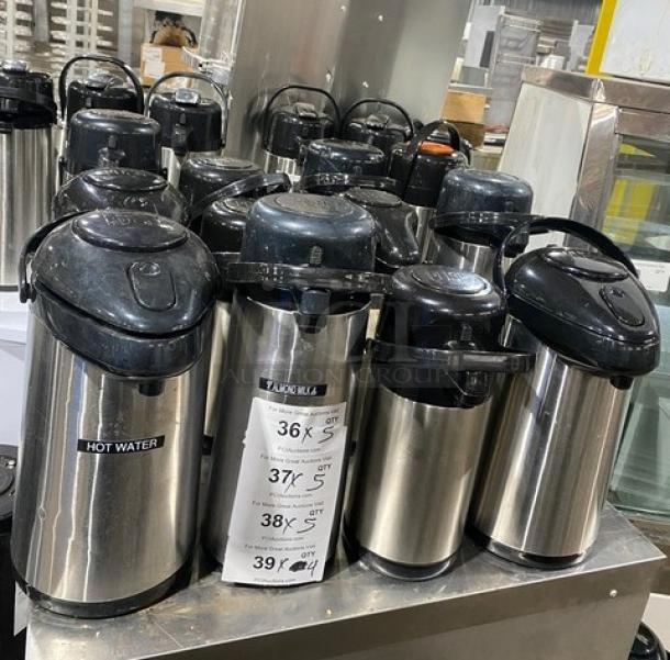 Commercial stainless steel insulated beverage dispensers in good condition, multiple units, black lids, various sizes labeled.