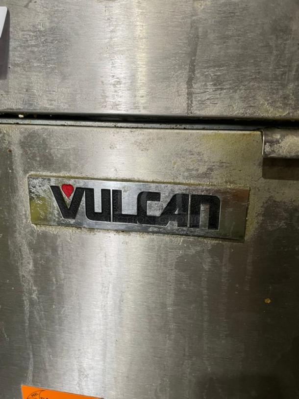 Vulcan 1VEG50M1 stainless steel natural gas fryer with backsplash, basket hanger, and on legs. Visible Vulcan logo, slightly worn condition.