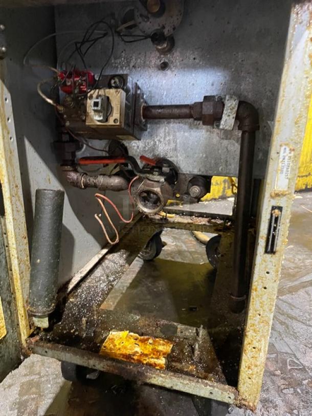 Frymaster PMJ135SD gas fryer interior; shows pipes and wiring. Rust and stains evident, used condition. On casters.
