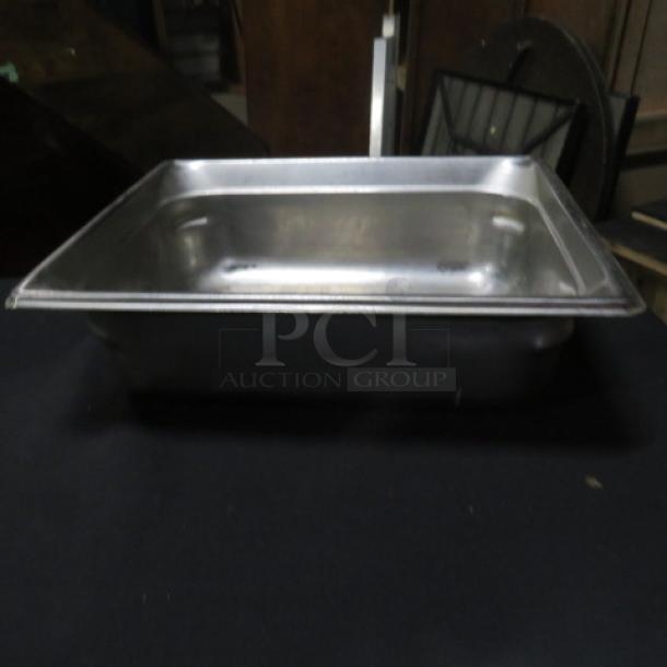 One half-size, 4-inch deep stainless steel hotel pan, in used condition, ideal for buffet or catering use.
