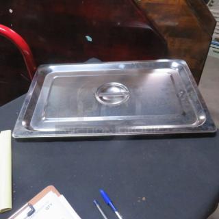 Stainless steel full-size hotel lid, new condition, with a center handle for easy lifting, placed on a black surface.
