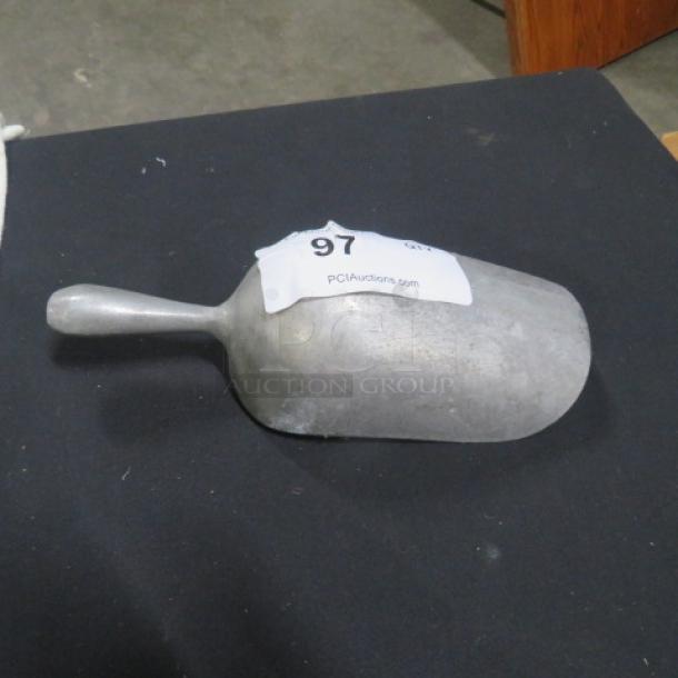 Aluminum scoop with a short handle, auction label "97" from PCIauctions.com, in good condition.