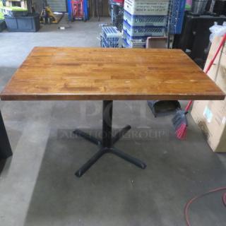 Solid wooden table top on a pedestal base, 48x30x29 inches. Features a polished finish. Good condition.