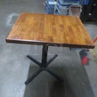 Solid wooden table top on a black pedestal base, measuring 30x24x29 inches. Wood finish, square shape, excellent condition.