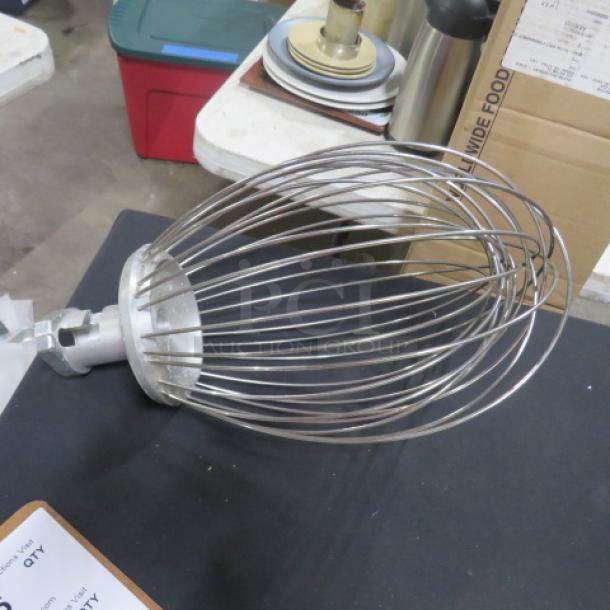Stainless steel industrial mixer whip in excellent condition, featuring sturdy wire construction and attachment hub.