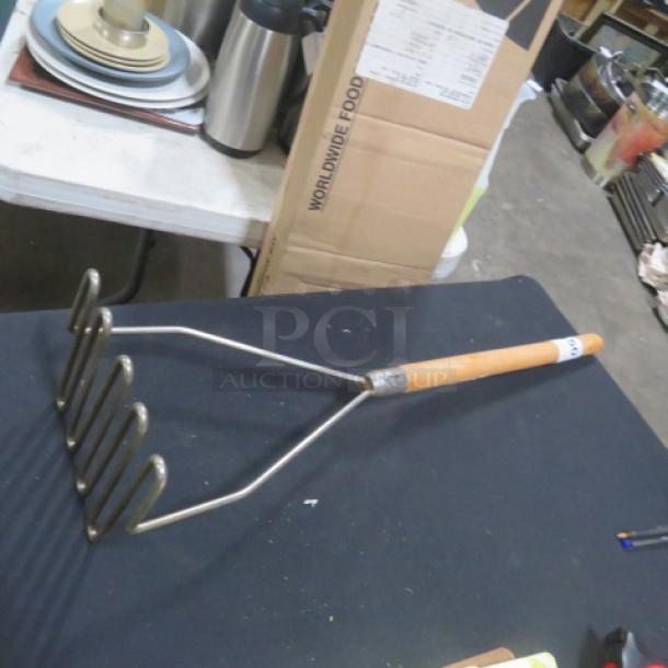 Wooden handle potato masher with metal mashing plate, good condition. Ideal for kitchen use, vintage appeal.