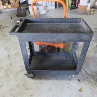 Black 2-shelf utility cart on casters, 34x17.5x33 inches, worn condition, sturdy design, ideal for storage and transport.