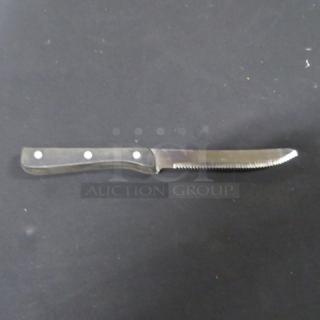 Serrated steak knife with a black handle, three rivets; shows minimal signs of wear.