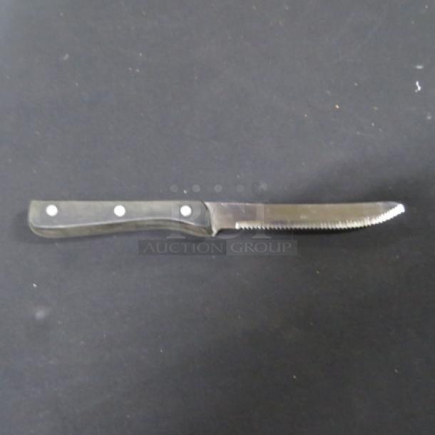 Steak knife with serrated stainless steel blade and black handle, 10XBID model, in good condition.