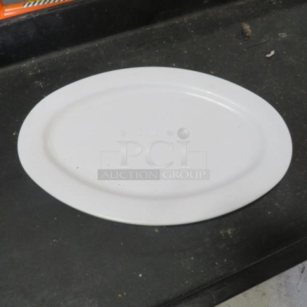 White 13.5x9.5-inch poly platter, oval shape. Minimal wear, smooth surface. Ideal for serving or display.