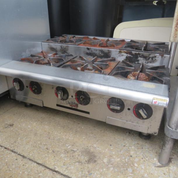 APW WYOTT tabletop 6-burner natural gas range, used condition. Measures 36"x32"x16". Features six control knobs; minor rust.