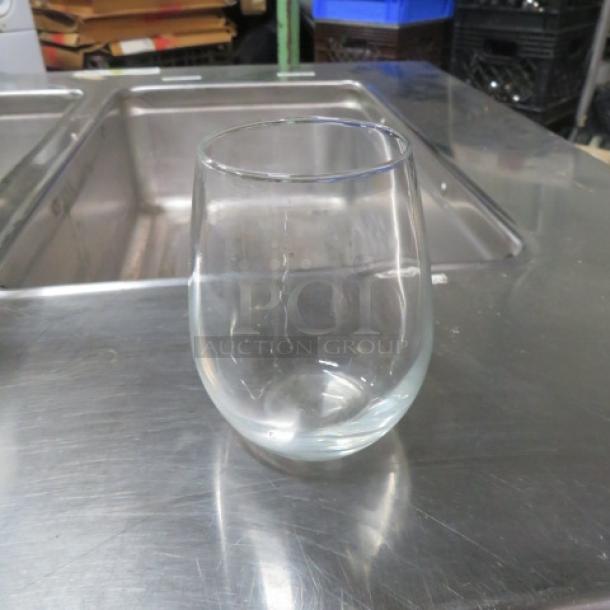 Clear stemless wine glass, smooth finish, used condition, approximately 5 inches tall, no visible markings or labels.