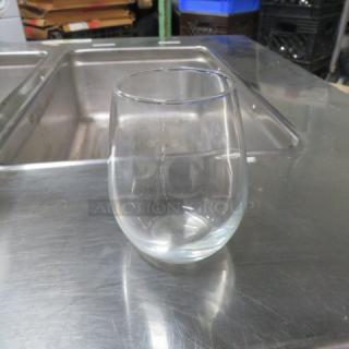 Clear stemless wine glass, smooth finish, used condition, approximately 5 inches tall, no visible markings or labels.