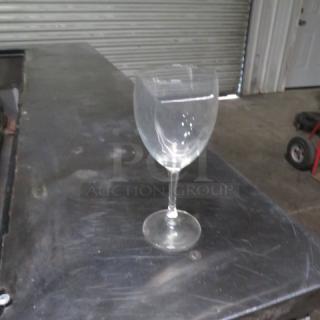 Clear stem wine glass, likely glass material, standing on a metal table. Appears in good condition. No visible markings.