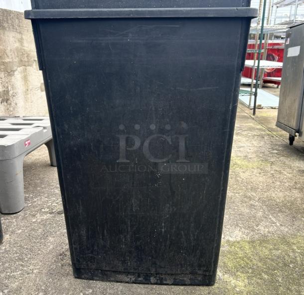 Black Slim Jim trash can, rectangular shape, used condition, slight scratches, outdoor setting.