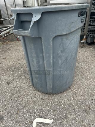 Rubbermaid Brute trash can, gray, with visible scuffs. Durable plastic, side handles. Ideal for industrial use.