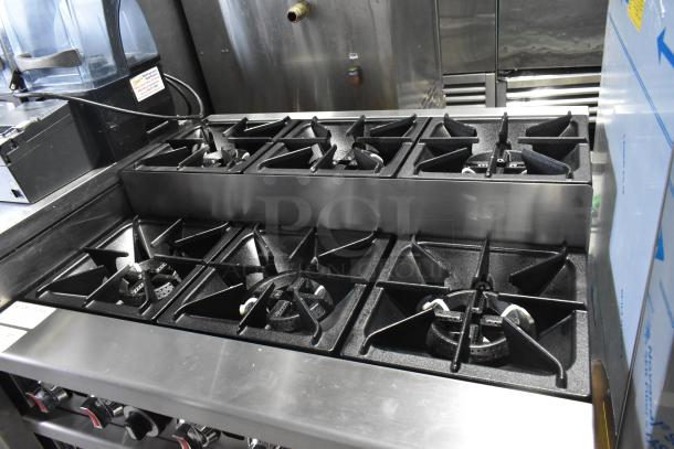 Stainless steel commercial gas range with 6 burners, oven, backsplash, over shelf. Model RC-ENR6B36TJ-NAT. 210,000 BTU.