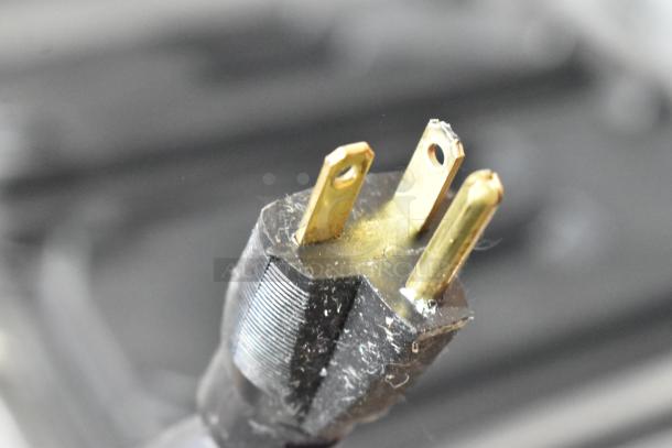 Close-up of a power plug from the Stoelting F131-38I2 soft serve machine, showing three prongs with slight wear, 208-240V.