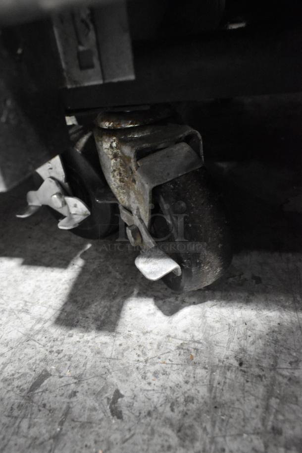 Close-up of a commercial caster wheel of a True T-23F stainless steel freezer. The wheel shows signs of wear.