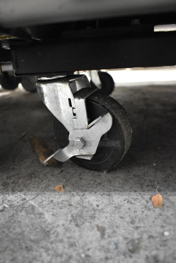 Close-up of a commercial caster on the 2018 True T-23F-HC stainless steel reach-in freezer, showing locking mechanism.