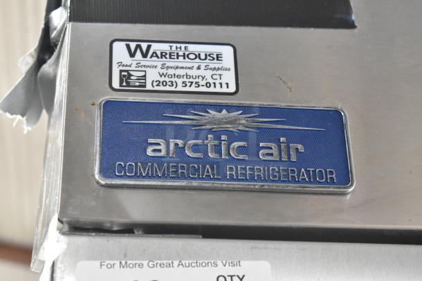Arctic Air AR49E commercial cooler badge, stainless steel, logo visible. Warehouse sticker indicates origin and contact info.