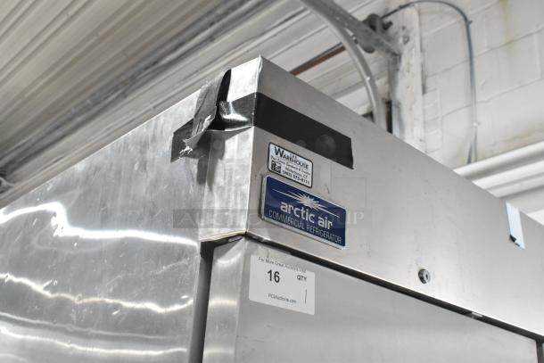Arctic Air AR49E stainless steel commercial cooler with poly rack and casters. Visible labels and tape on door. 115V, 1 phase.