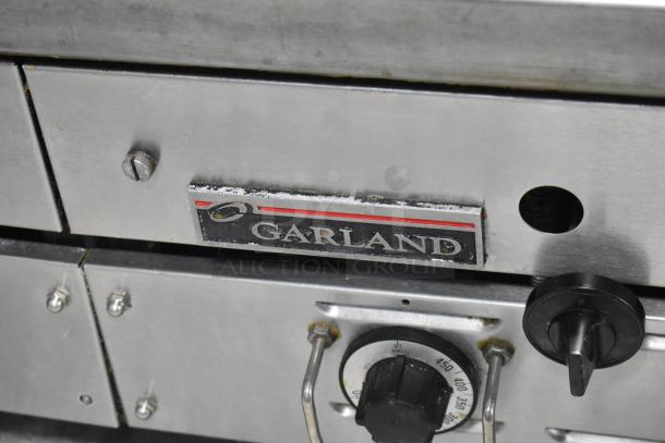 Garland stainless steel gas-powered flat top griddle, commercial countertop model. Features a temperature control dial and Garland logo.