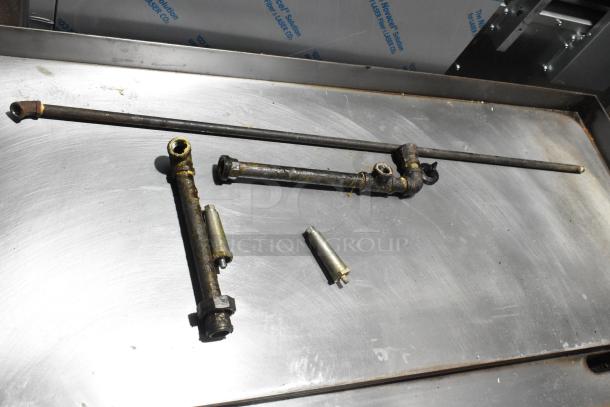 Garland stainless steel countertop gas griddle parts on metal surface, showing wear and rust.