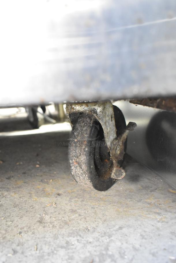 True TUC-60 cooler caster wheel, showing rust and wear. Part of a 2-door stainless steel undercounter unit.
